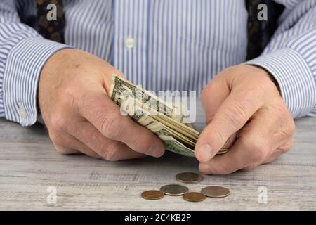 close up of an elderly man's rough hands counting his dollar bills and pocket change Stock Photo