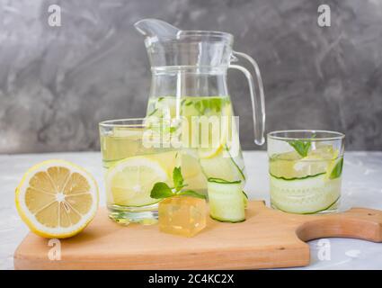 Carafe and two glasses on a wooden board. lemon and ice with mint. copyspace Stock Photo