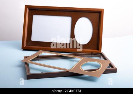 an empty wooden photo frame and mat with another frame open on a blue table Stock Photo