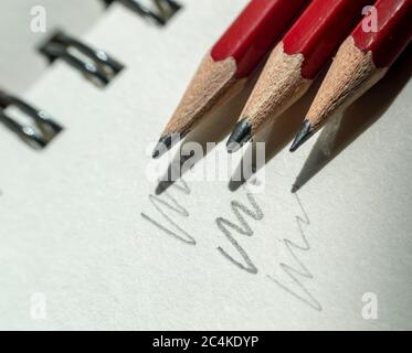 Close-up of three pencils diagonally placed on a sketch pad Stock Photo