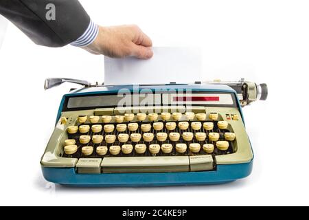 a business man hand pulling a sheet of paper from an old grungy manual portable typewriter with copy space Stock Photo