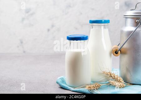 Two glass bottles of fresh skimmed milk and aluminum milk can on a table Stock Photo