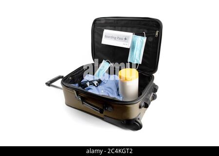 a carry on suitcase with a generic boarding pass, a surgical maskand disinfecting wipes suggesting the new normal for air travel after covid-19 corona Stock Photo
