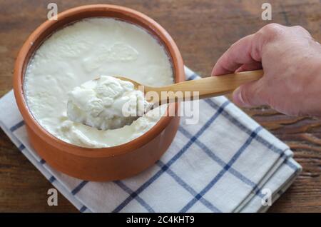 Traditional Turkish Yogurt in earthen pot on the wooden table. Stock Photo