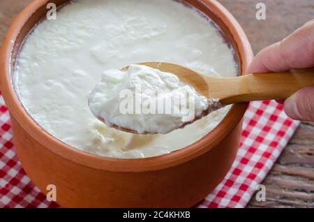 Traditional Turkish Yogurt in earthen pot on the wooden table. Stock Photo