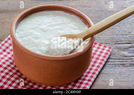 Traditional Turkish Yogurt in earthen pot on the wooden table. Stock Photo