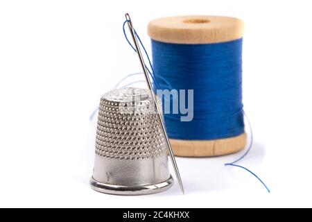 closeup of a sewing thimble with a needle and blue thread isolated on white Stock Photo