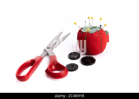 a red pin cushion with black buttons and tailoring scissors isolated on white Stock Photo