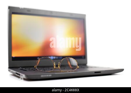 a notebook computer with a pair of reading glasses on the keyboard isolated on white Stock Photo
