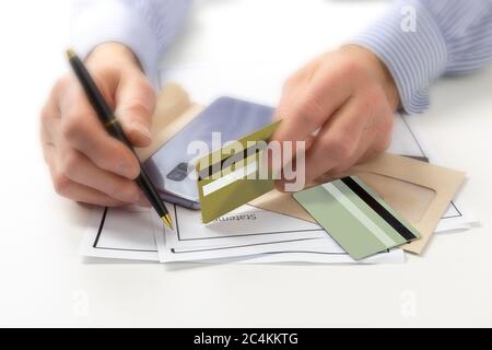 a man with several credit cards checks his statement with a pen on a white background Stock Photo