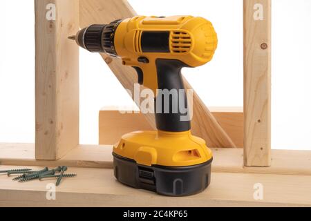 a yellow battery operated drill and construction screws in a residential construction framing setting isolated on white Stock Photo