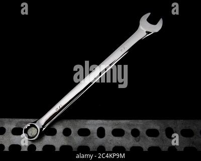 the open end of a combination box and open end wrench on a bolt head on a black background Stock Photo