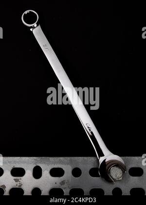 the open end of a combination box and open end wrench on a bolt head on a black background Stock Photo