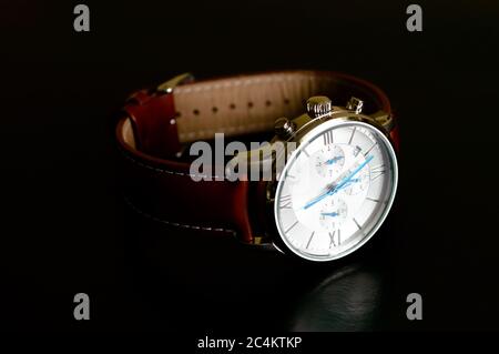 Nice luxury man's wrist watch with blue clock hands and brown leather strap on black background Stock Photo