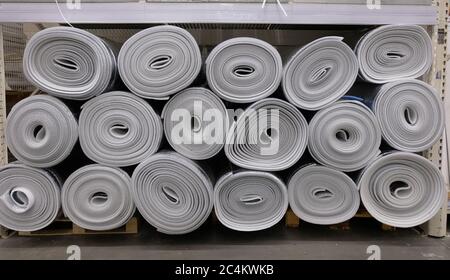 Stacked rolls of insulating material material closed cell black color with aluminum foil on one side in warehouse. Stock Photo