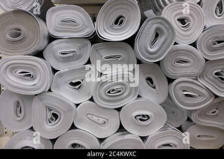 Stacked rolls of insulating material material closed cell black color with aluminum foil on one side in warehouse. Stock Photo