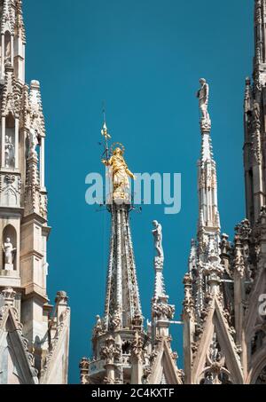 Milan Cathedral spires, Italy. Golden statue of Madonna on blue sky background. Famous Milan Cathedral or Duomo di Milano is top landmark of old Milan Stock Photo