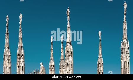 Milan Cathedral roof, Italy. Famous Milan Cathedral or Duomo di Milano is a top landmark of Milan. Many luxury spires with statues on blue sky backgro Stock Photo
