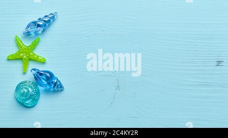 Glass seashells and starfish on a blue wooden background with copy space Stock Photo