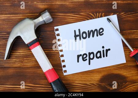 Repairman working tools with a sticker and an inscription on it home repair on a white wooden background. Stock Photo