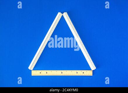 a triangle formed by three rulers on a bright blue background Stock Photo