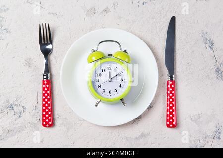 Green retro alarm clock with bells on the plate with fork and knife, lunch time concept, top view with copy space Stock Photo
