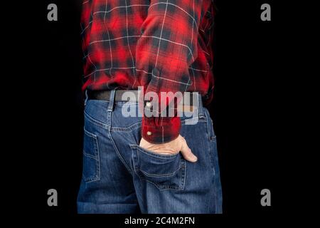 a man in blue denim jeans and a red plaid shirt with one hand in the rear pocket on black Stock Photo