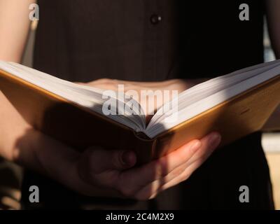 Book in hands close up in daylight. The person is reading an interesting book Stock Photo