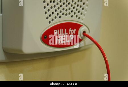 Close view of a red cord and button that can be pulled in case of an emergency, located in a private bathroom in a hospital. Stock Photo