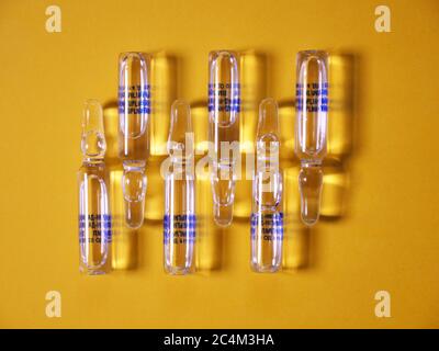Ampoule on a yellow background for the treatment of Coronavirus Covid19 Stock Photo