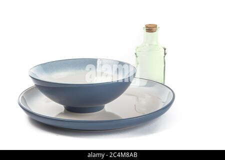 a blue soup bowl on a blue dinner plate with a bottle for olive oil isolated on white Stock Photo