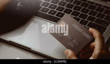 Clos up hands holding credit card and using laptop. Online shopping and paying concept. Stock Photo