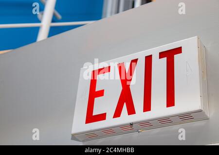 A perspective view from a low angle showing a red "EXIT" sign on a white wall. Stock Photo