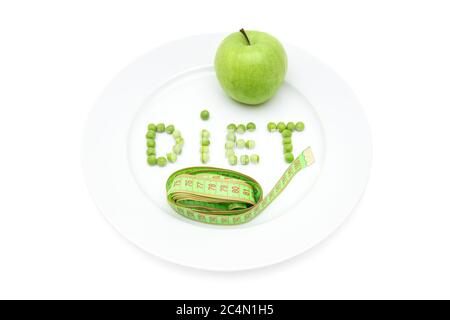 Word DIET made of garden peas on a large white plate, fresh green apple and a soft tape measure isolated on white. Detox, weight loss and dieting conc Stock Photo