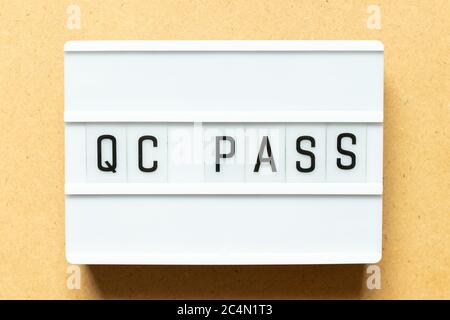 Lightbox with word QC (Abbreviation of Quality Control) pass on wood background Stock Photo