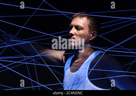 Picture of man tangled in white threads in neon light Stock Photo