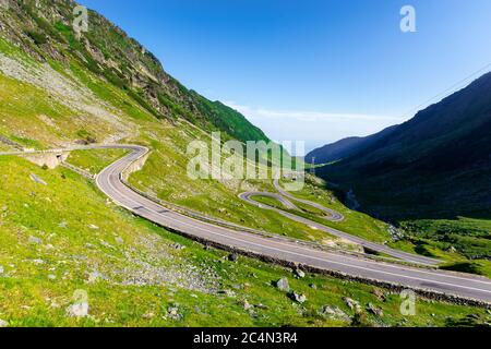 winding mountain road on a sunny day. empty highway run through valley. open vista in the distance. great european journey in summertime concept. Stock Photo