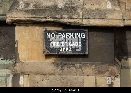 A worn down sign saying, "No Parking Fire Brigade Only" on a sandstone wall Stock Photo
