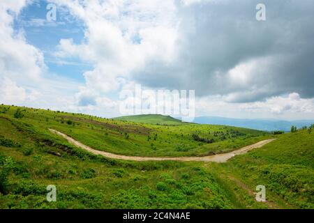 path through mountain landscape. road through green rolling hills. cloudy weather Stock Photo