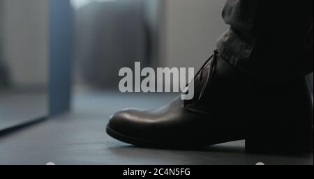 Young man put on his brown leather chukka boots indoor Stock Photo