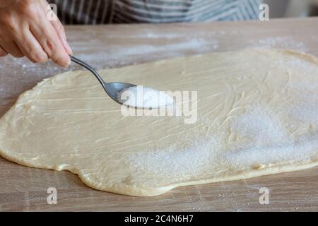 sugar is poured on the yeast dough, process of making sweet rolls Stock Photo