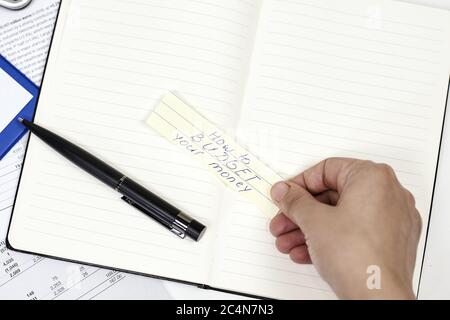 Man holding  piece of paper with the words "how to budget your money" on it Stock Photo