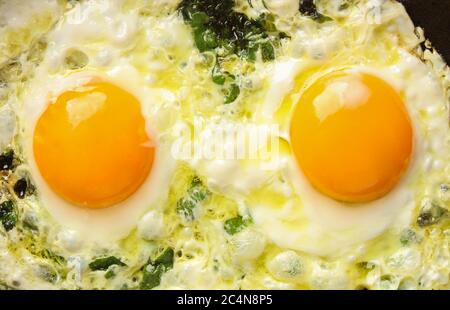 Fried eggs with spinach in a pan. View from above Stock Photo