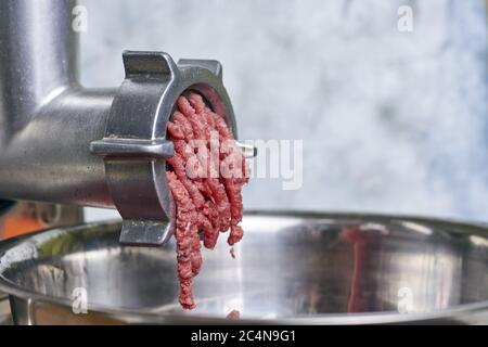 Closeup of ground meat coming out of an electric meat grinder Stock Photo