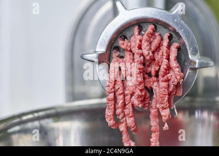 Closeup of ground meat coming out of an electric meat grinder Stock Photo