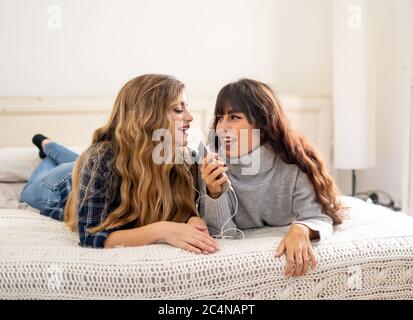 COVID-19 Lockdown. Portrait of confident and positive women girlfriends listening online music together on mobile phone during coronavirus social dist Stock Photo