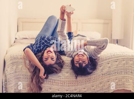 COVID-19 Lockdown. Portrait of confident and positive women girlfriends listening online music together on mobile phone during coronavirus social dist Stock Photo