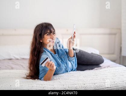 COVID-19 Outbreak. Shutdown and online shopping. Attractive young woman with credit card using mobile smartphone buying food on the internet at home d Stock Photo