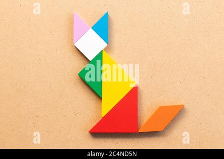 Color tangram puzzle in sitting cat shape on wood bacground Stock Photo