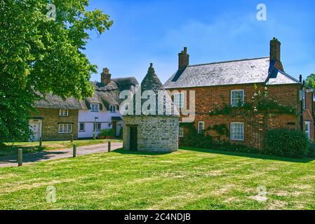 The Old Village Lock Up Gaol or Blind House surrounded by cottages on the green in Harrold, Bedfordshire, UK Stock Photo